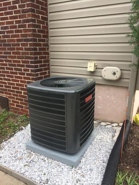 AC condenser on concrete pad with clean wiring at brick home